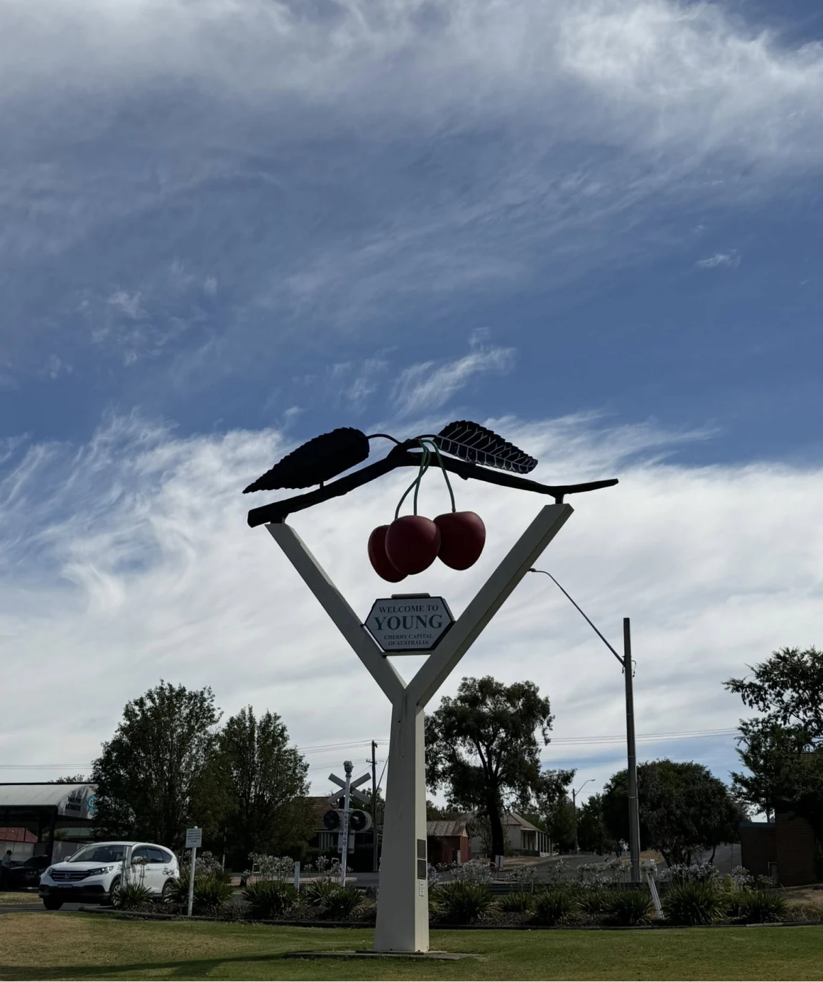Cherry sculpture under a cloudy sky.