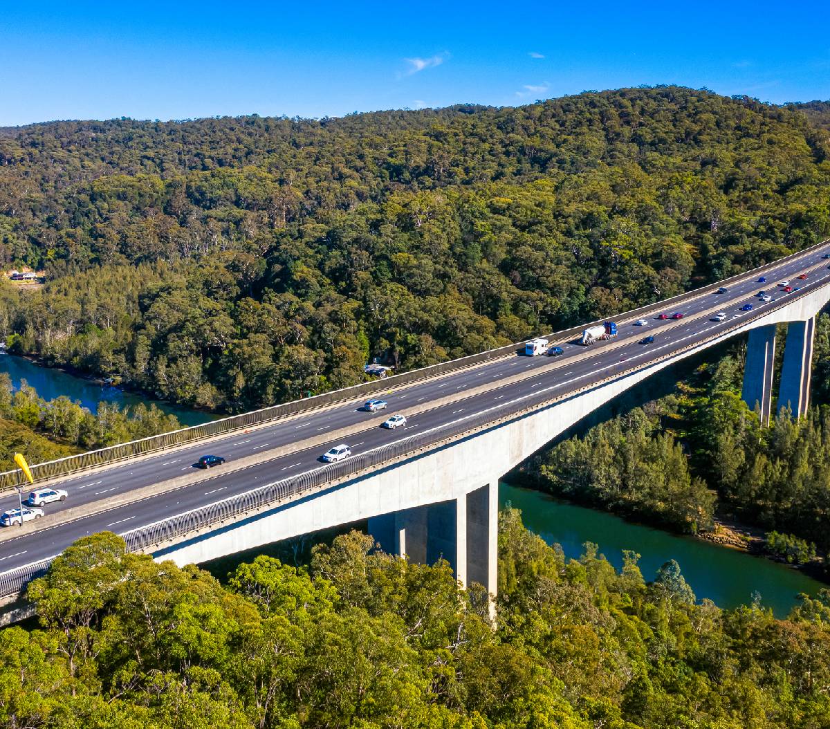 Aerial view of a highway bridge crossing over a lush forest and river