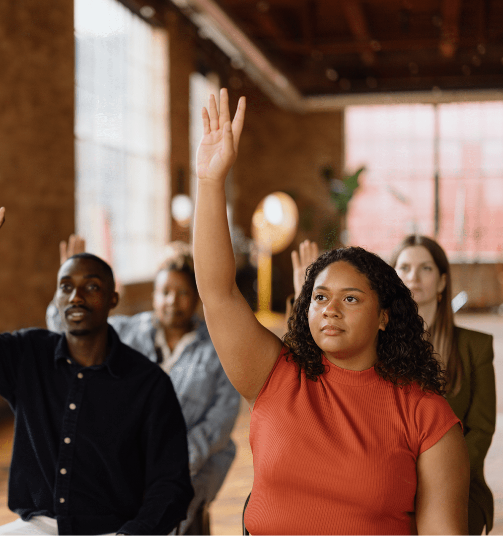 People raising hands in a meeting room.