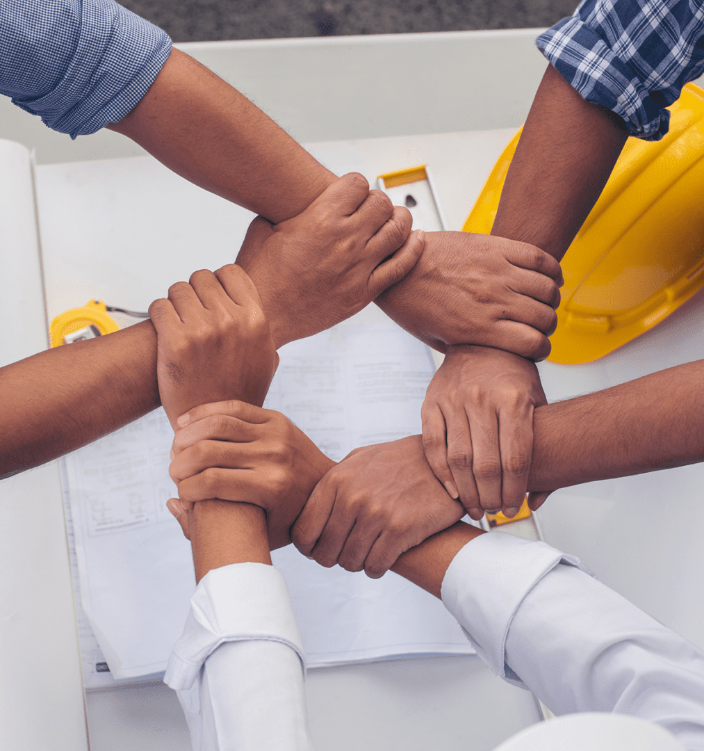Hands joined in teamwork over construction plans.
