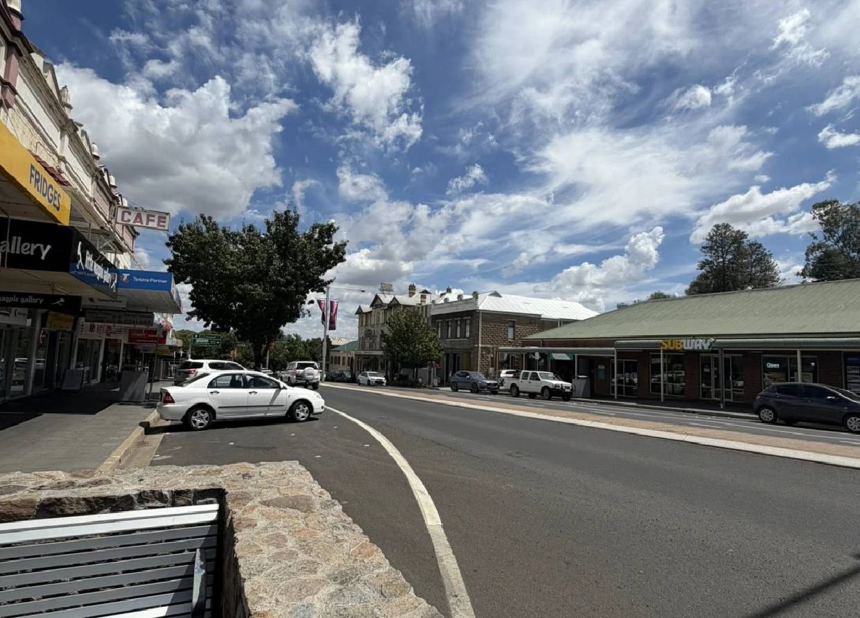A small town street bathed in sunlight with parked cars