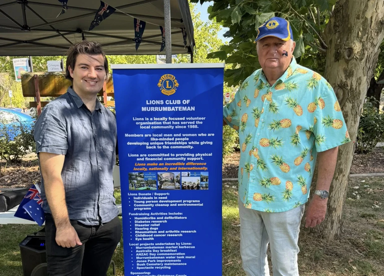 Two men beside Lions Club banner outdoors.